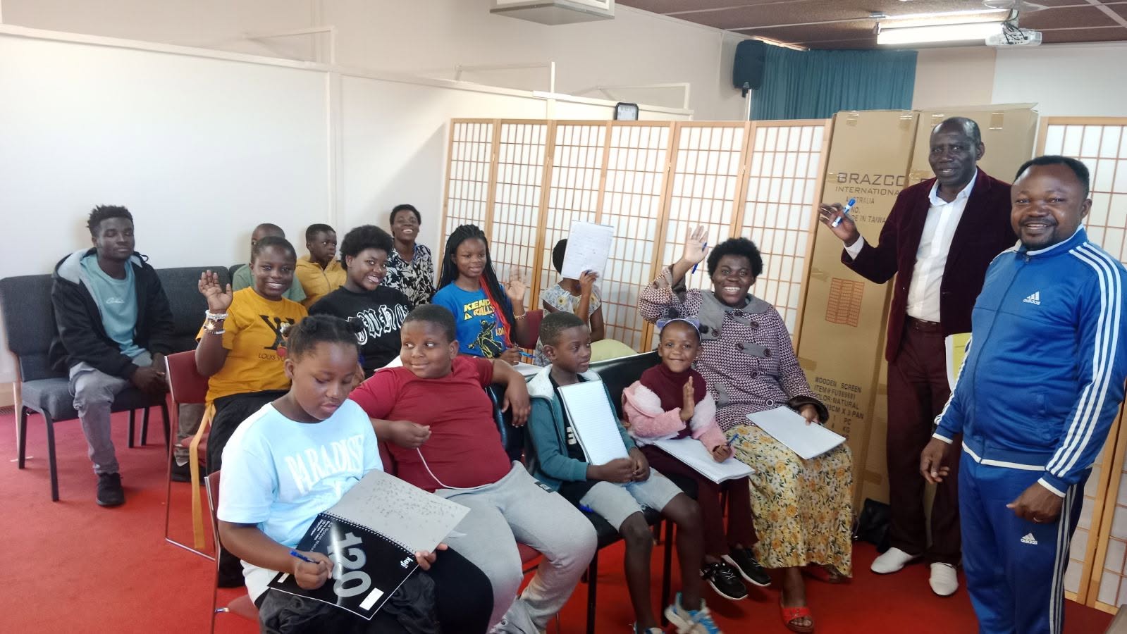 Children and adults waving during a community class at the Congolese Cultural School